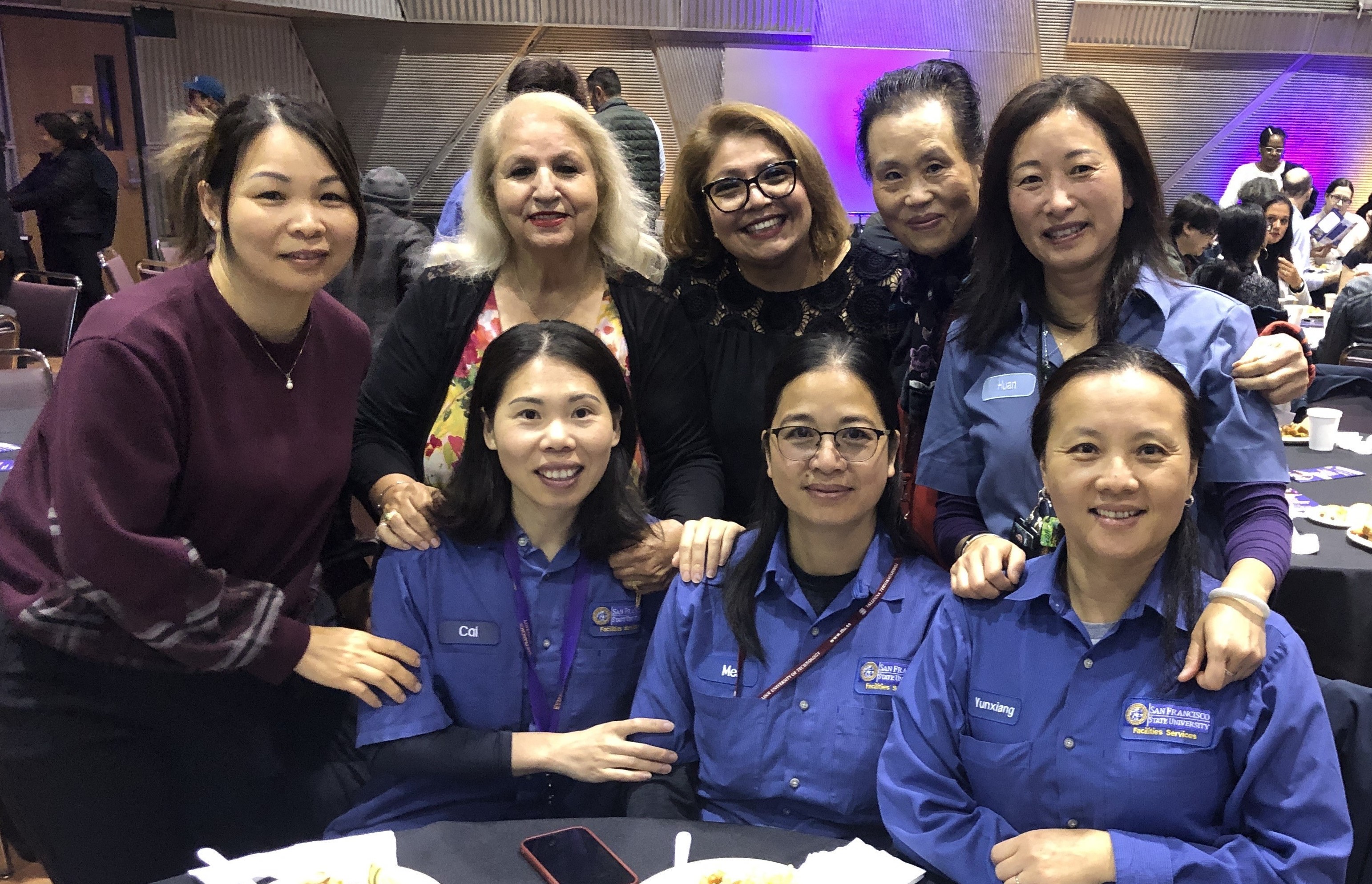 8 employees sitting together at a table eating 